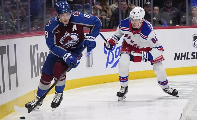 Colorado Avalanche defenseman Cale Makar, left, collects the puck as New York Rangers center Adam Edstrom defends in the second period of an NHL hockey game Tuesday, Jan. 14, 2025, in Denver. (AP Photo/David Zalubowski)