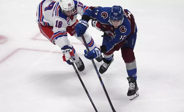 Colorado Avalanche center Parker Kelly, right, collects the puck as New York Rangers defenseman Urho Vaakanainen defends in the first period of an NHL hockey game Tuesday, Jan. 14, 2025, in Denver. (AP Photo/David Zalubowski)