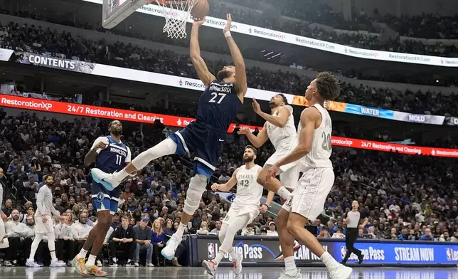 Minnesota Timberwolves center Rudy Gobert (27) shoots as teammate center Naz Reid (11) looks on against Dallas Mavericks defenders Kessler Edwards (20), Quentin Grimes (5) and Maxi Kleber (42) during the first half of an NBA basketball game Wednesday, Jan. 22, 2025, in Dallas. (AP Photo/LM Otero)