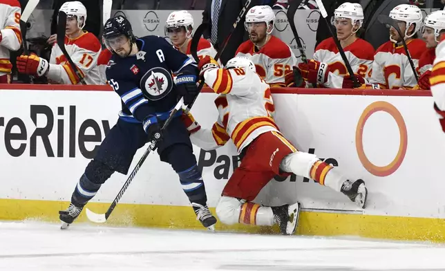 Calgary Flames' Jakob Pelletier is checked by Winnipeg Jets' Mark Scheifele during the second period of an NHL hockey game in Winnipeg, Manitoba, Sunday, Jan. 26, 2025. (Fred Greenslade/The Canadian Press via AP)