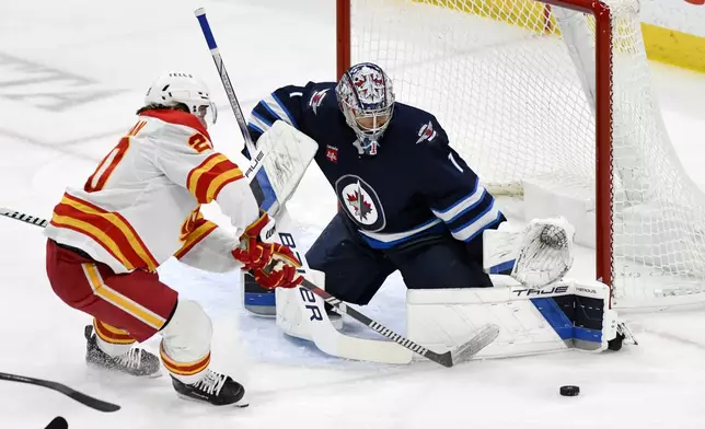 Winnipeg Jets' goaltender Eric Comrie (1) makes a save on Calgary Flames' Blake Coleman during the first period of an NHL hockey game in Winnipeg, Manitoba, Sunday, Jan. 26, 2025. (Fred Greenslade/The Canadian Press via AP)