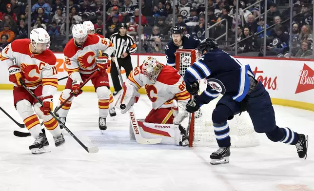 Calgary Flames goaltender Dan Vladar (80) makes a save against Winnipeg Jets' Rasmus Kupari (15) during the second period of an NHL hockey game in Winnipeg, Manitoba, Sunday, Jan. 26, 2025. (Fred Greenslade/The Canadian Press via AP)