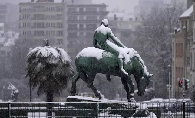 A statue and palm tree are covered in snow after early morning snow fell in the center of Brussels, Thursday, Jan. 9, 2025. (AP Photo/Virginia Mayo)