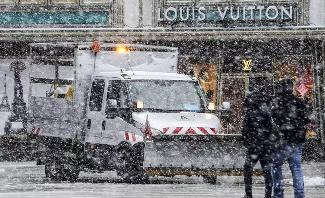 A clearing vehicle drives in the city center during heavy snowfall in Cologne, Germany, Thursday, Jan. 9, 2025. (AP Photo/Martin Meissner)