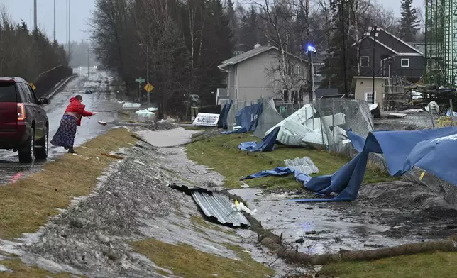 A woman tosses debris from a construction site that was on Brayton Drive during the windstorm on Sunday, Jan. 12, 2025. (Bill Roth/Anchorage Daily News via AP)
