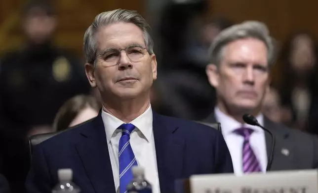 Scott Bessent, left, President-elect Donald Trump's choice to be Secretary of the Treasury, appears before the Senate Finance Committee for his confirmation hearing as his husband John Freeman, right, listens at the Capitol in Washington, Thursday, Jan. 16, 2025. (AP Photo/Ben Curtis)