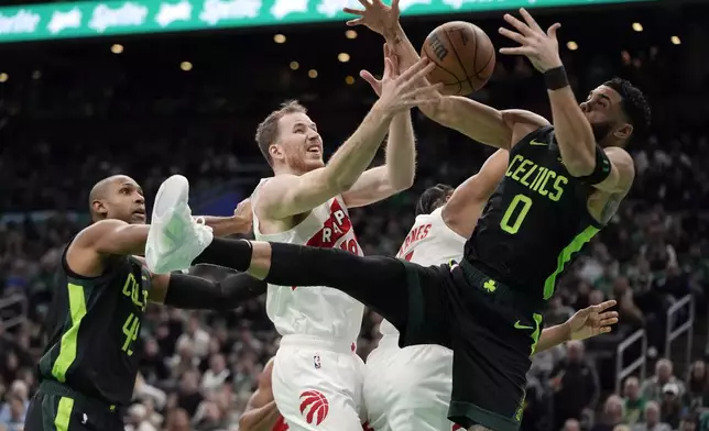 Toronto Raptors' Jakob Poeltl (19) battles Boston Celtics' Jayson Tatum (0) for a rebound during the first half of an NBA basketball game, Tuesday, Dec. 31, 2024, in Boston. (AP Photo/Michael Dwyer)