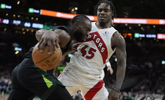 Boston Celtics' Jaylen Brown, left, drives past Toronto Raptors' Davion Mitchell (45) during the second half of an NBA basketball game, Tuesday, Dec. 31, 2024, in Boston. (AP Photo/Michael Dwyer)