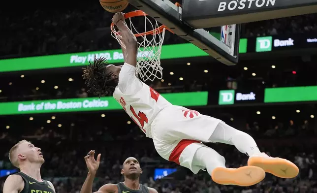 Toronto Raptors' Ja'Kobe Walter (14) misses his dunk in front of Boston Celtics' Sam Hauser, left, and Al Horford during the first half of an NBA basketball game, Tuesday, Dec. 31, 2024, in Boston. (AP Photo/Michael Dwyer)