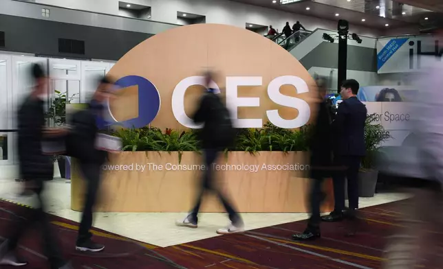 People walk by a sign ahead of the CES tech show Monday, Jan. 6, 2025, in Las Vegas. (AP Photo/John Locher)