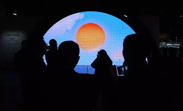 People watch a video displayed on a screen at a LG Electronics booth during the CES tech show Tuesday, Jan. 7, 2025, in Las Vegas. (AP Photo/Abbie Parr)