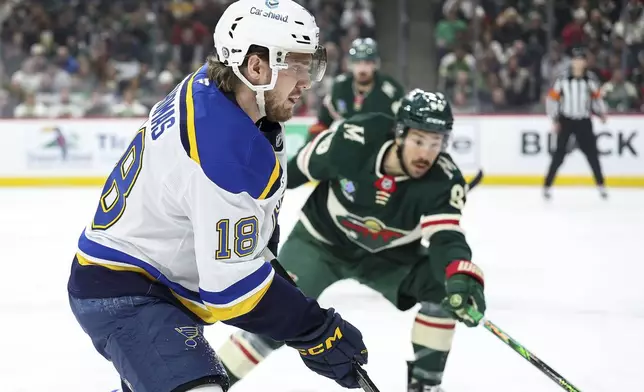 St. Louis Blues center Robert Thomas (18) skates with the puck as Minnesota Wild center Frederick Gaudreau defends during the first period of an NHL hockey game Tuesday, Jan. 7, 2025, in St. Paul, Minn. (AP Photo/Matt Krohn)