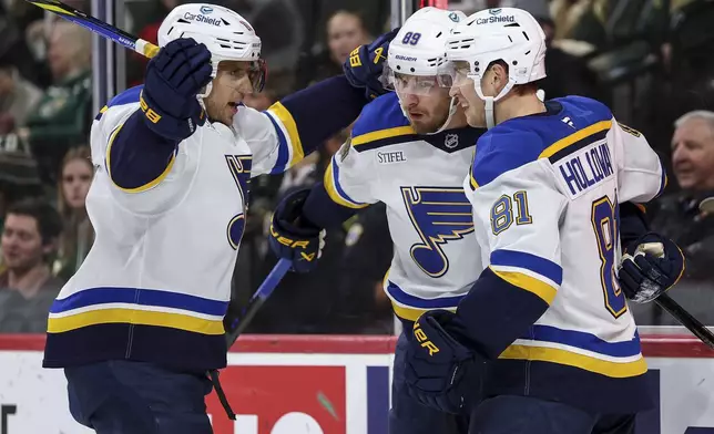 St. Louis Blues left wing Pavel Buchnevich, middle, celebrates his goal with centers Brayden Schenn, left, and Dylan Holloway during the first period of an NHL hockey game against the Minnesota Wild, Tuesday, Jan. 7, 2025, in St. Paul, Minn. (AP Photo/Matt Krohn)