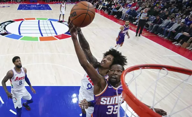 Phoenix Suns' Kevin Durant, right, and Philadelphia 76ers' Kelly Oubre Jr. reach for a rebound during the second half of an NBA basketball game, Monday, Jan. 6, 2025, in Philadelphia. (AP Photo/Matt Slocum)