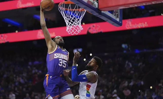 Phoenix Suns' Kevin Durant, left, dunks against Philadelphia 76ers' Paul George during the second half of an NBA basketball game, Monday, Jan. 6, 2025, in Philadelphia. (AP Photo/Matt Slocum)