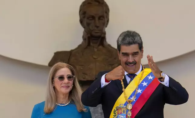 Venezuelan President Nicolas Maduro gestures to supporters next to his wife Cilia Flores after his swearing-in ceremony for a third term at the National Assembly in Caracas, Venezuela, Friday, Jan. 10, 2025. (AP Photo/Ariana Cubillos)