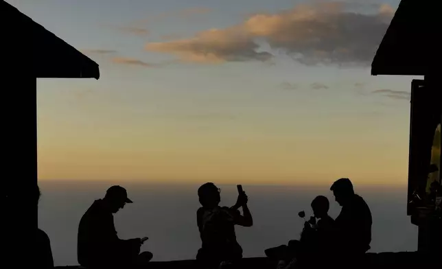 A family gathers on top of a mountain in El Avila National Park in La Guaira, Venezuela, Wednesday, Jan. 8, 2025, days ahead of President Nicolas Maduro's inauguration for a third presidential term. (AP Photo/Matias Delacroix)