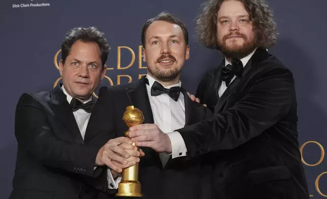 Ron Dyens, from left, Gints Zilbalodis, and Matiss Kaza pose in the press room with the award for best motion picture - animated for "Flow" during the 82nd Golden Globes on Sunday, Jan. 5, 2025, at the Beverly Hilton in Beverly Hills, Calif. (AP Photo/Chris Pizzello)