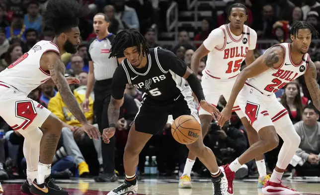 San Antonio Spurs guard Stephon Castle (5) controls the ball as Chicago Bulls guard Coby White, left, guards during the first half of an NBA basketball game in Chicago, Monday, Jan. 6, 2025. (AP Photo/Nam Y. Huh)