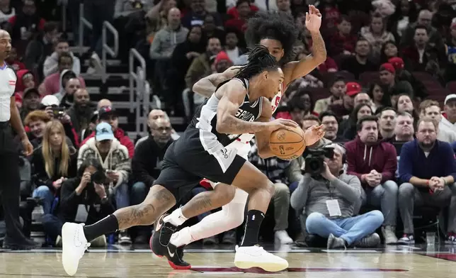 San Antonio Spurs guard Devin Vassell, front, drives against Chicago Bulls guard Coby White, back, during the first half of an NBA basketball game in Chicago, Monday, Jan. 6, 2025. (AP Photo/Nam Y. Huh)