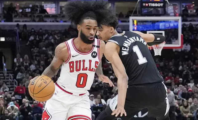 Chicago Bulls guard Coby White, left, drives to the basket past San Antonio Spurs center Victor Wembanyama, right, during the first half of an NBA basketball game in Chicago, Monday, Jan. 6, 2025. (AP Photo/Nam Y. Huh)