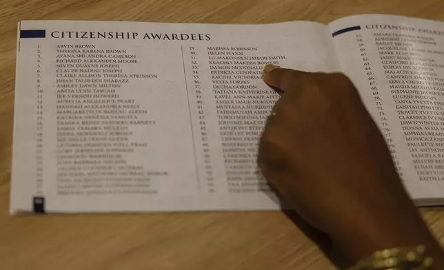 Keachia Bowers points to her name in a booklet listing people who are part of the Black diaspora and obtained citizenship in Ghana at a ceremony the previous month, in Accra, Ghana, Friday, Dec. 6, 2024. Bowers’ family of four relocated to Ghana from Florida and have obtained Ghanaian citizenship. (AP Photo/Misper Apawu)