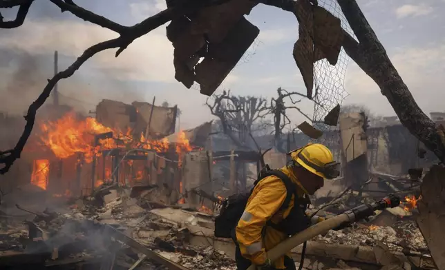 A firefighter battles the Palisades Fire around a burned structure in the Pacific Palisades neighborhood of Los Angeles, Wednesday, Jan. 8, 2025. (AP Photo/Etienne Laurent)