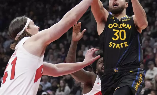 Golden State Warriors guard Stephen Curry (30) drives to the net past Toronto Raptors forward Kelly Olynyk (41) during first-half NBA basketball game action in Toronto, Monday, Jan. 13, 2025. (Nathan Denette/The Canadian Press via AP)