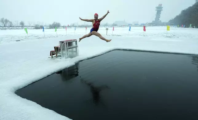 Yu Xiaofeng leaps as she jumps into a pool carved from ice on the frozen Songhua river in Harbin in northeastern China's Heilongjiang province, Tuesday, Jan. 7, 2025. (AP Photo/Andy Wong)