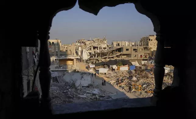 Palestinians walk through the destruction in the wake of an Israeli air and ground offensive in Khan Younis, southern Gaza Strip, Tuesday, Jan. 7, 2025. (AP Photo/Abdel Kareem Hana)