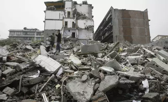 FILE -Residents try to use mobile phone to call their missing relatives as they search for survivors amonst the rubble of a collapsed building in Dujiangyan, southwest China's Sichuan Province, May 15, 2008. (AP Photo/Vincent Yu, File)