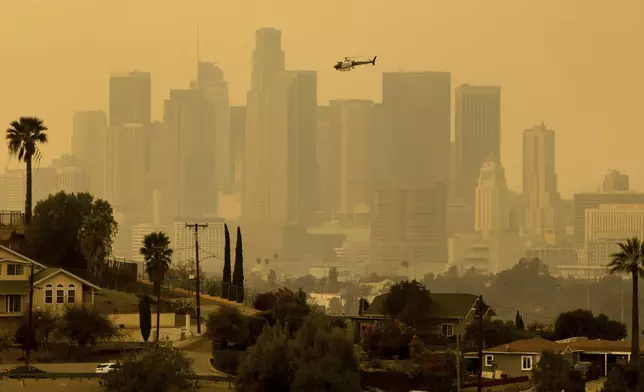 The sky is filled with smoke from multiple wildfires around the city skyline Thursday, Jan. 9, 2025, in Los Angeles. (AP Photo/Etienne Laurent)