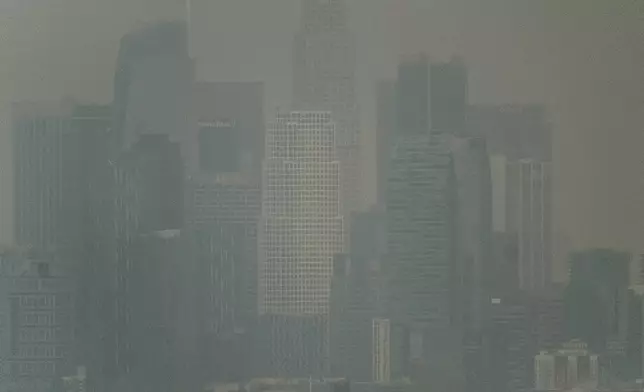 Thick heavy black smoke from wildfires shrouds buildings in downtown Los Angeles on Wednesday, Jan. 8, 2025. (AP Photo/Richard Vogel)