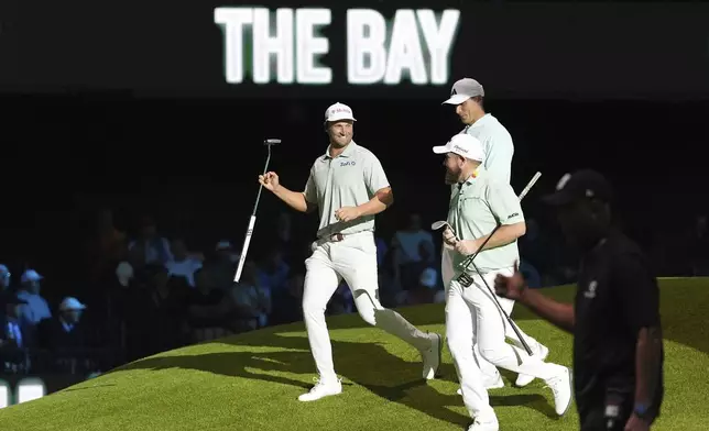 The Bay Golf Club's Wyndham Clark, left, and teammates Ludvig Aberg, top, and Shane Lowry celebrate winning the third hole during the inaugural match of the TMRW Golf League, Tuesday, Jan. 7, 2025, in Palm Beach Gardens, Fla. TGL features six teams of four players competing against each other in a tech-infused arena the size of a football field. (AP Photo/Rebecca Blackwell)