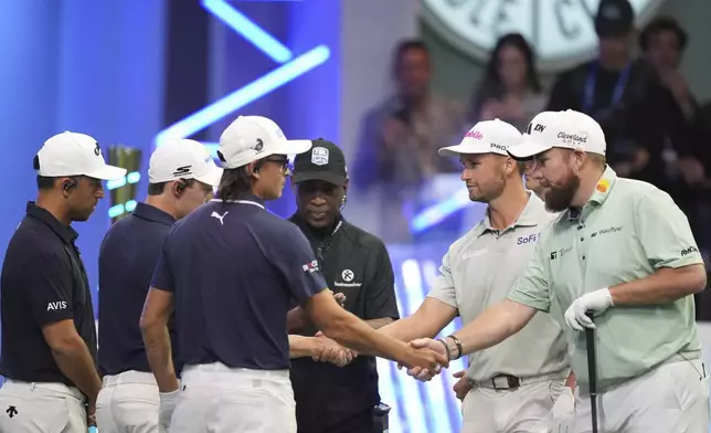 Rickie Fowler of New York Golf Club, third left, shakes hands with Shane Lowry of The Bay Golf Club as the teams prepare for the start of the inaugural match of the TMRW Golf League, Tuesday, Jan. 7, 2025, in Palm Beach Gardens, Fla. TGL features six teams of four players competing against each other in a tech-infused arena the size of a football field. (AP Photo/Rebecca Blackwell)