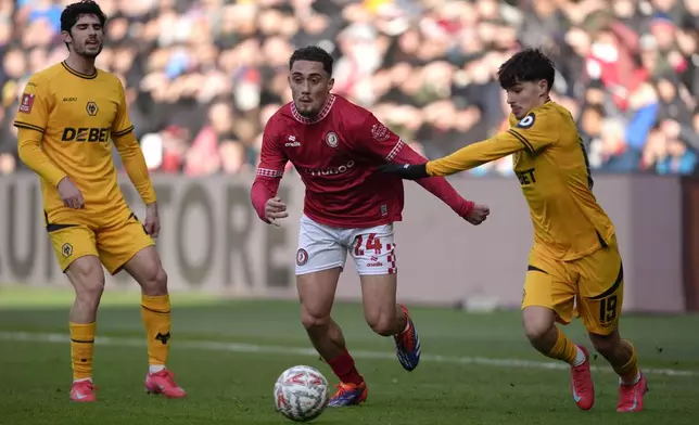 Bristol City's Haydon Roberts, center and Wolverhampton Wanderers' Rodrigo Gomes, right, vie for the ball, during the English FA Cup third round soccer match between Bristol City and Wolverhampton Wanderers, at Ashton Gate, in Bristol, England, Saturday, Jan. 11, 2025. (Nick Potts/PA via AP)