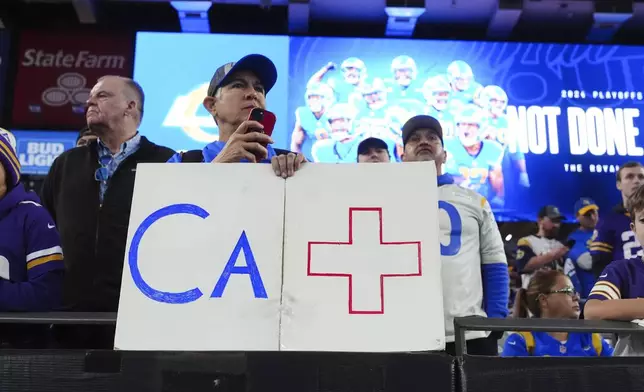 A Los Angeles Rams fan holds a sign b before an NFL wild card playoff football game against the Minnesota Vikings, Monday, Jan. 13, 2025, in Glendale, Ariz. (AP Photo/Ross D. Franklin)