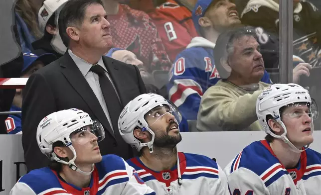 New York Rangers head coach Peter Laviolette, rear left, watches a replay during the second period of an NHL hockey game against the Washington Capitals, Saturday, Jan. 4, 2025, in Washington. (AP Photo/John McDonnell)