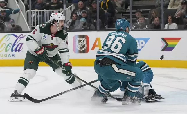 Minnesota Wild defenseman Jake Middleton, left, misses a shot against San Jose Sharks defenseman Jake Walman (96) and goaltender Yaroslav Askarov, back right, during the second period of an NHL hockey game in San Jose, Calif., Saturday, Jan. 11, 2025. (AP Photo/Jeff Chiu)