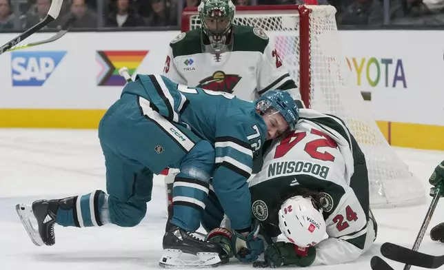 San Jose Sharks left wing William Eklund (72) reaches for the puck over Minnesota Wild defenseman Zach Bogosian (24) during the first period of an NHL hockey game in San Jose, Calif., Saturday, Jan. 11, 2025. (AP Photo/Jeff Chiu)