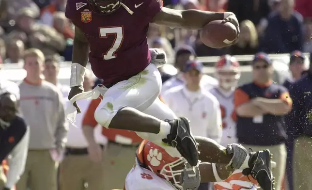 FILE - Virginia Tech quarterback Michael Vick (7) eludes Clemson's Keith Adams for a short gain in the first quarter of the Gator Bowl in Jacksonville, Fla., Monday, Jan. 1, 2001. Michael Vick, (AP Photo/Steve Helber, File)