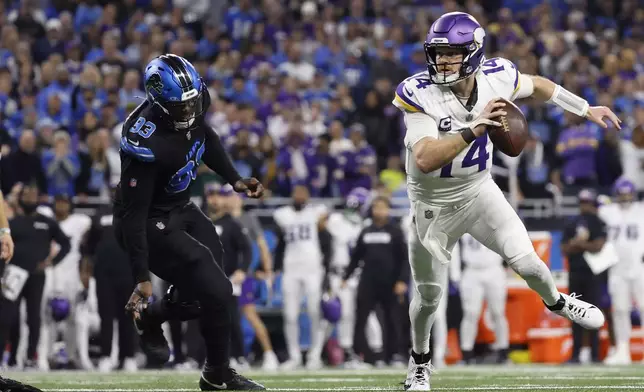 Minnesota Vikings quarterback Sam Darnold (14) looks to as he is pressured by Detroit Lions defensive end Josh Paschal (93) during the second half of an NFL football game Sunday, Jan. 5, 2025, in Detroit. (AP Photo/Rey Del Rio)