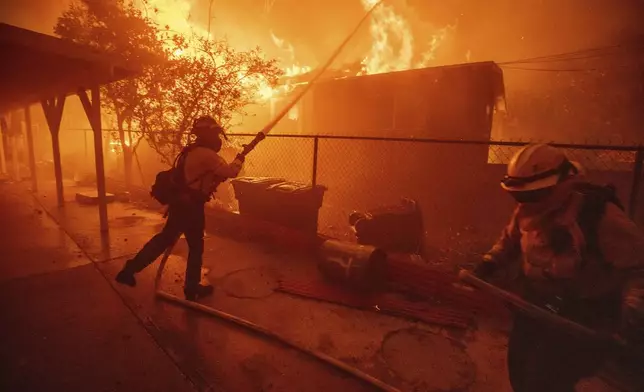 Firefighters protect a structure as the Eaton Fire advances Wednesday, Jan. 8, 2025 in Altadena, Calif. (AP Photo/Ethan Swope)