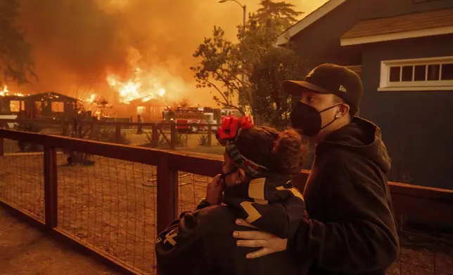 People watch as the Eaton Fire destroys a neigborhood Wednesday, Jan. 8, 2025 in Altadena, Calif. (AP Photo/Ethan Swope)