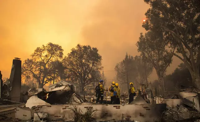 Firefighters work inside a burned structure while battling the Eaton Fire, Wednesday, Jan. 8, 2025, in Altadena, Calif. (AP Photo/Nic Coury)