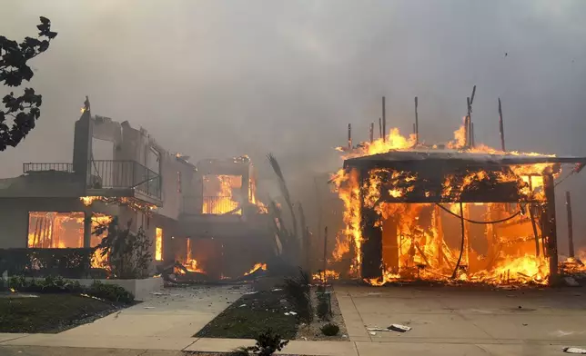 The Palisades Fire ravages a neighborhood amid high winds in the Pacific Palisades neighborhood of Los Angeles, Wednesday, Jan. 8, 2025. (AP Photo/Damian Dovarganes)