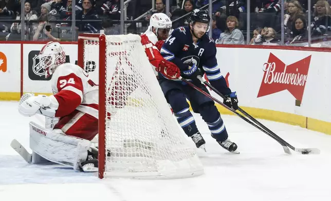 Detroit Red Wings' Andrew Copp (18) defends against Winnipeg Jets' Josh Morrissey (44) as goaltender Alex Lyon (34) looks on during second period NHL action in Winnipeg, Saturday, Jan. 4, 2025. (John Woods/The Canadian Press via AP)