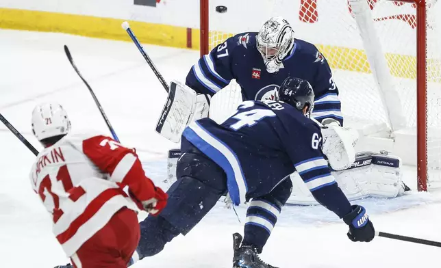 Detroit Red Wings' Dylan Larkin (71) scores against Winnipeg Jets goaltender Connor Hellebuyck (37) during first-period NHL hockey game action in Winnipeg, Manitoba, Saturday, Jan. 4, 2025. (John Woods/The Canadian Press via AP)