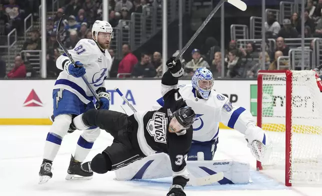 Tampa Bay Lightning goaltender Andrei Vasilevskiy, right, deflects a shot as Los Angeles Kings left wing Warren Foegele, center, is shoves to the ice by defenseman Erik Cernak during the second period of an NHL hockey game, Saturday, Jan. 4, 2025, in Los Angeles. (AP Photo/Mark J. Terrill)