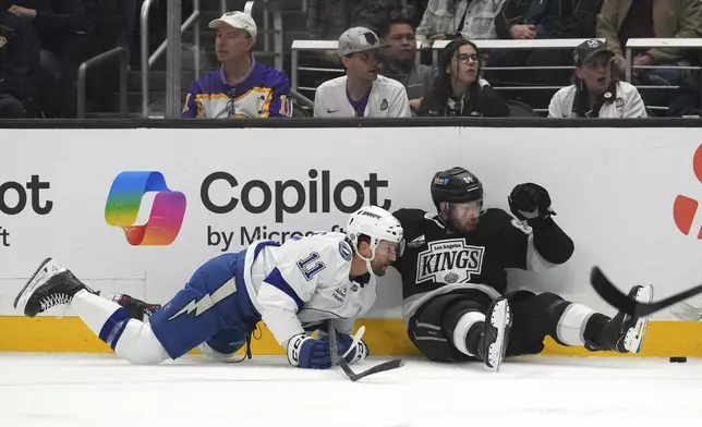 Tampa Bay Lightning center Luke Glendening, left, and Los Angeles Kings defenseman Vladislav Gavrikov fall as they vie for the puck during the first period of an NHL hockey game, Saturday, Jan. 4, 2025, in Los Angeles. (AP Photo/Mark J. Terrill)